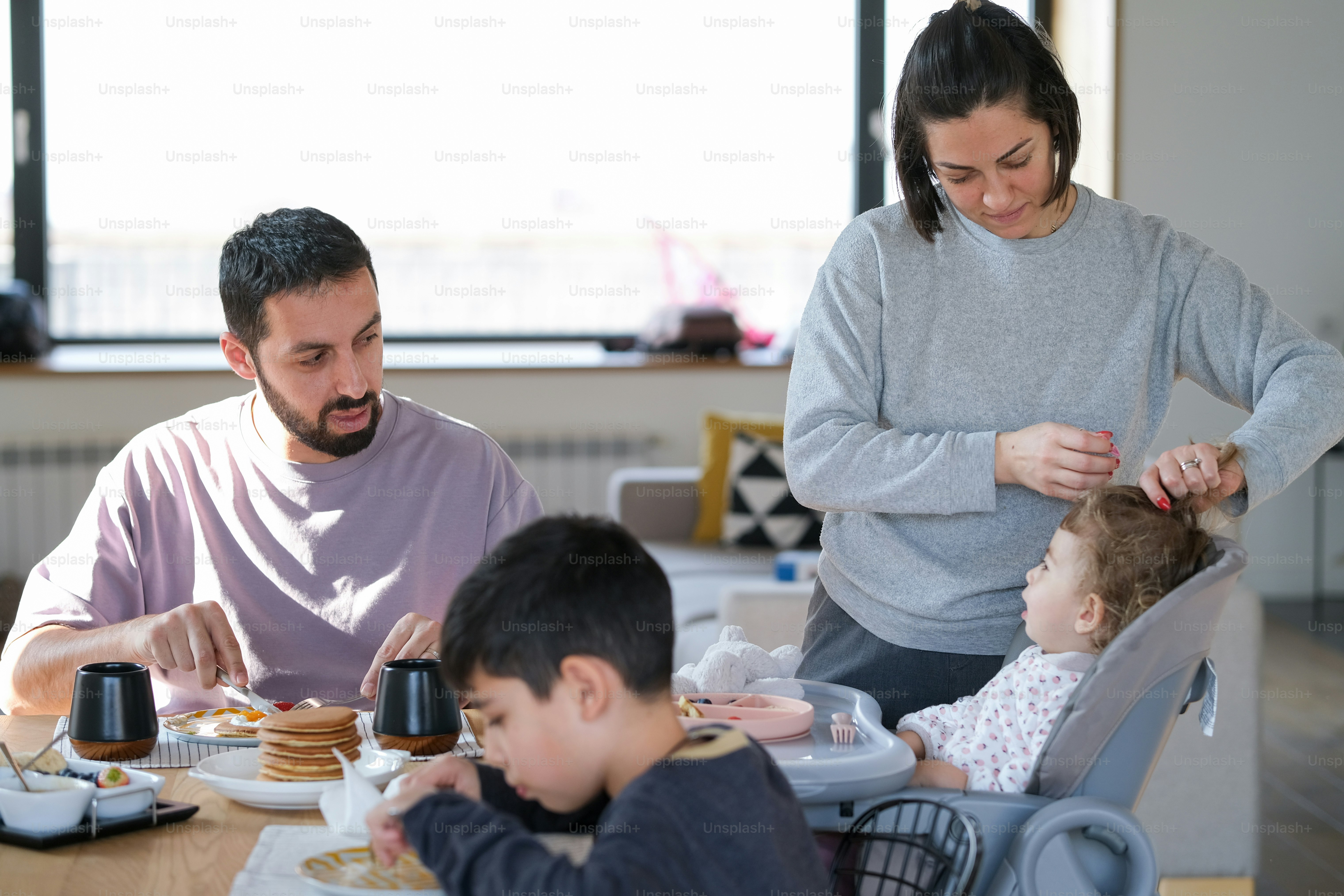 a woman and two children sitting at a table with plates of food