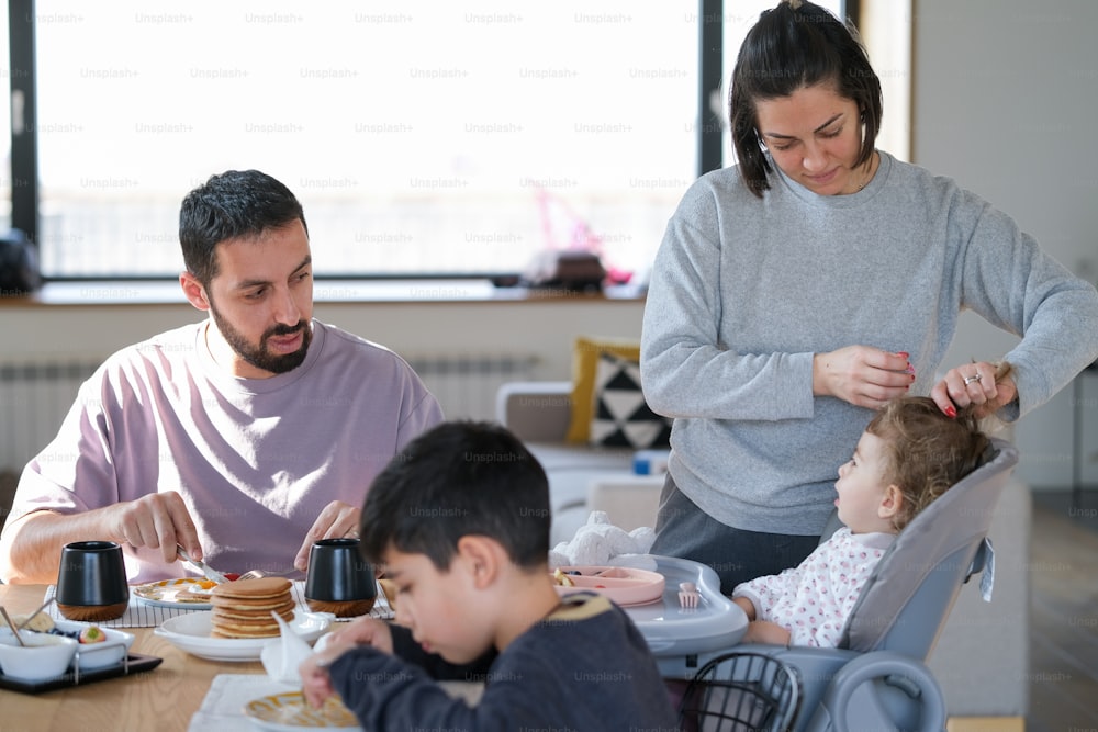Una mujer y dos niños sentados en una mesa con platos de comida