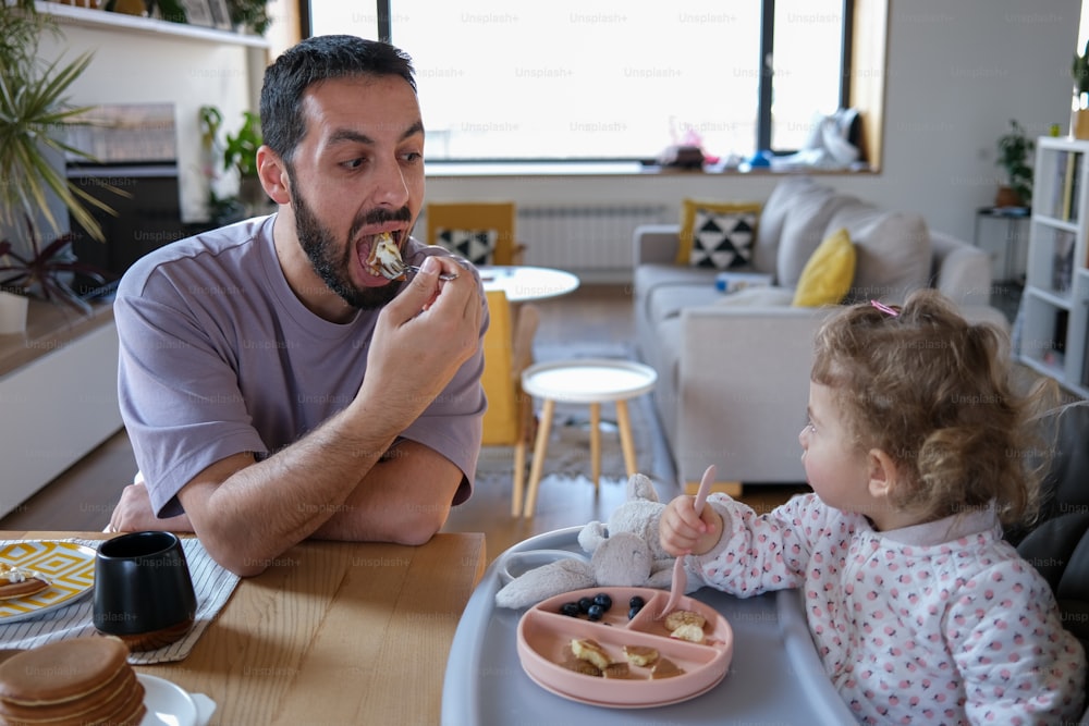 um homem sentado em uma mesa com um bebê comendo comida
