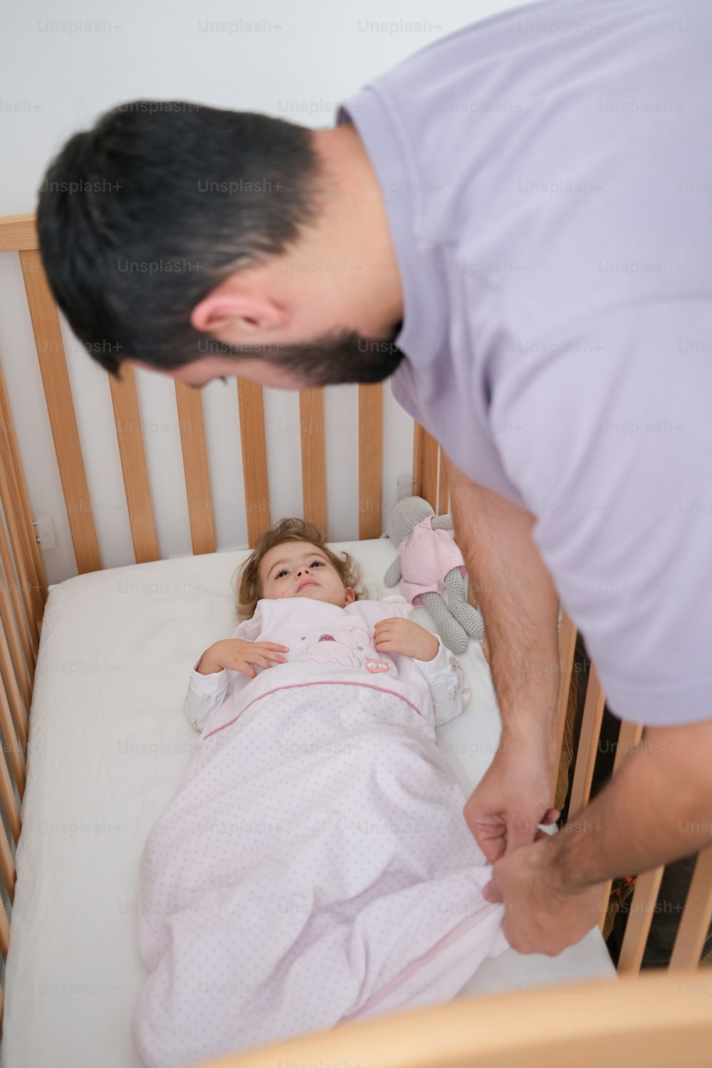 a man standing over a little girl in a crib