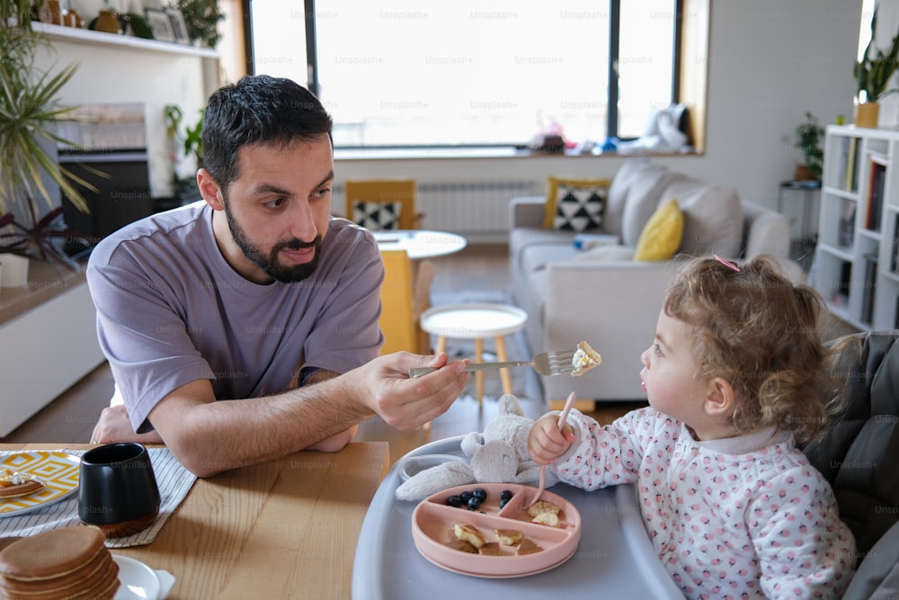 Un hombre alimentando a una niña con un pedazo de pastel