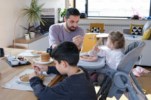 a man sitting at a table with two children