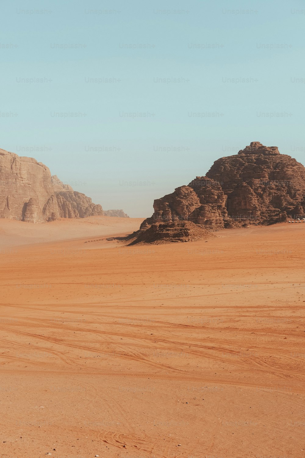 uma paisagem do deserto com uma montanha no fundo