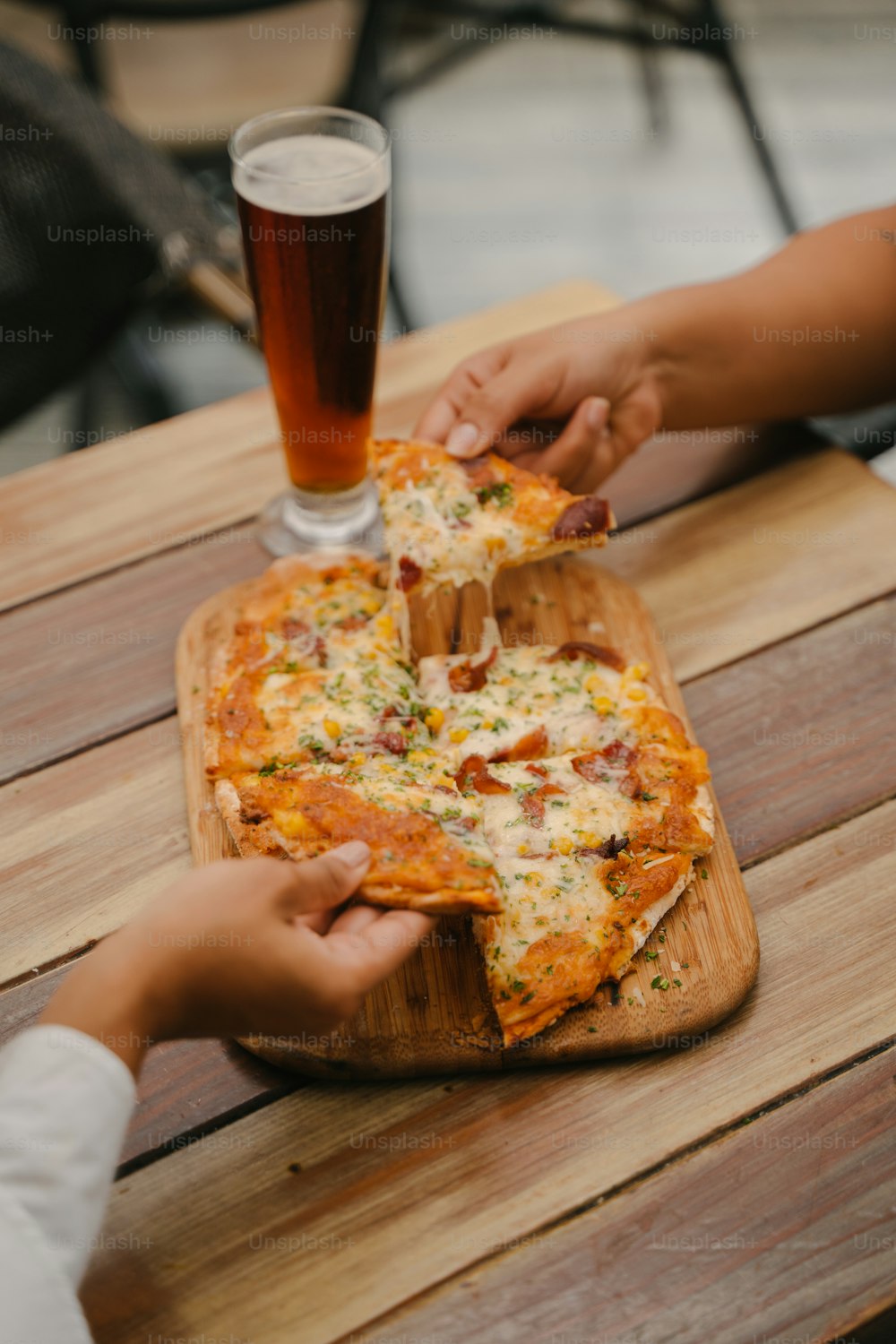 ein Holztisch mit einer Pizza und einem Glas Bier