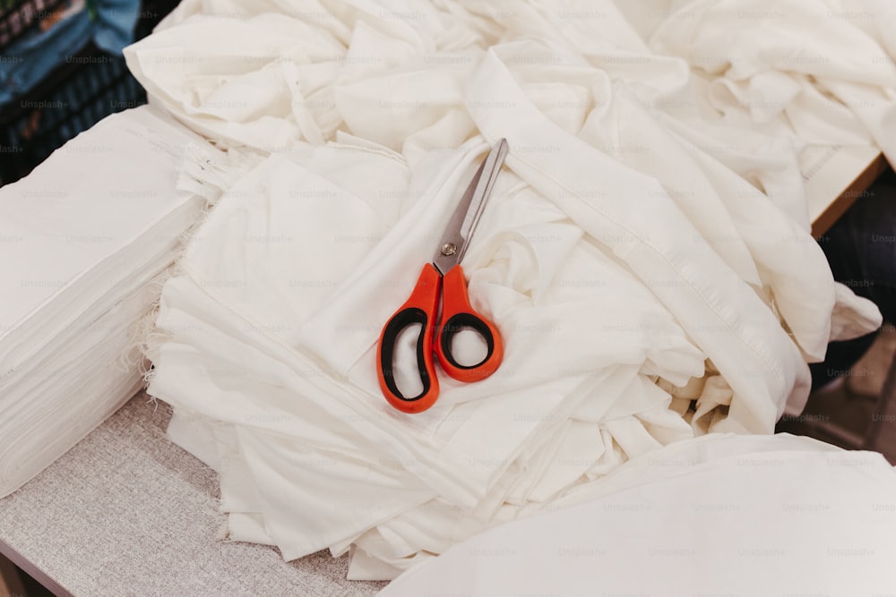 a pair of scissors sitting on top of a pile of cloth