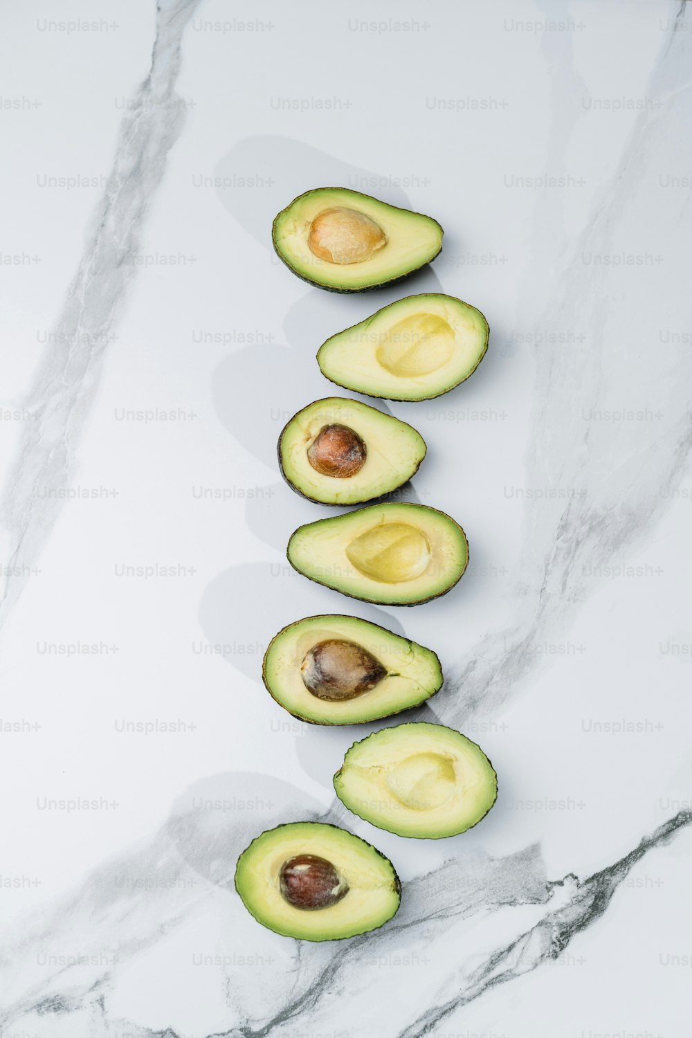an avocado cut in half on a marble counter top