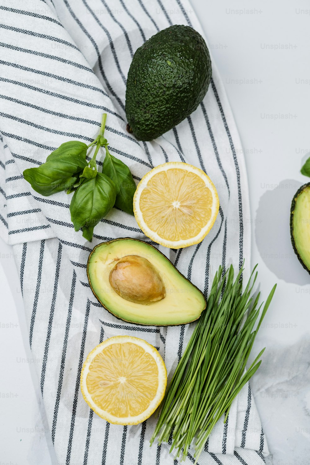 an avocado, lemons, and greens on a towel