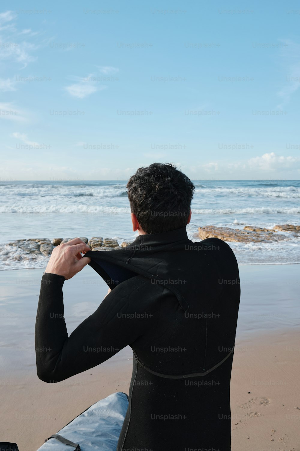 a man in a wet suit is sitting on a surfboard