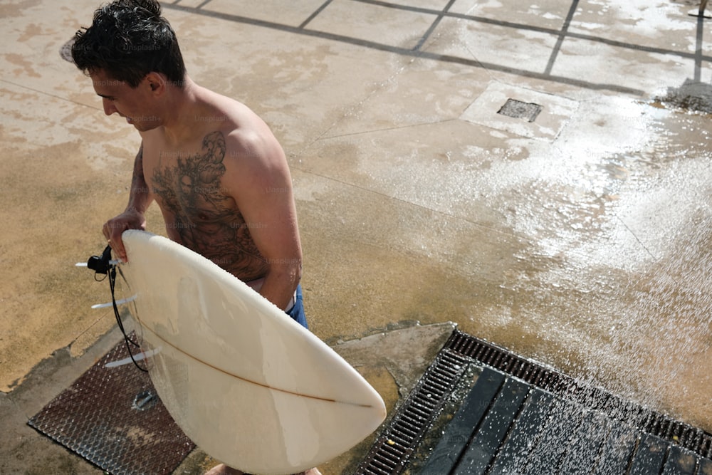 a man holding a white surfboard on top of a wet ground