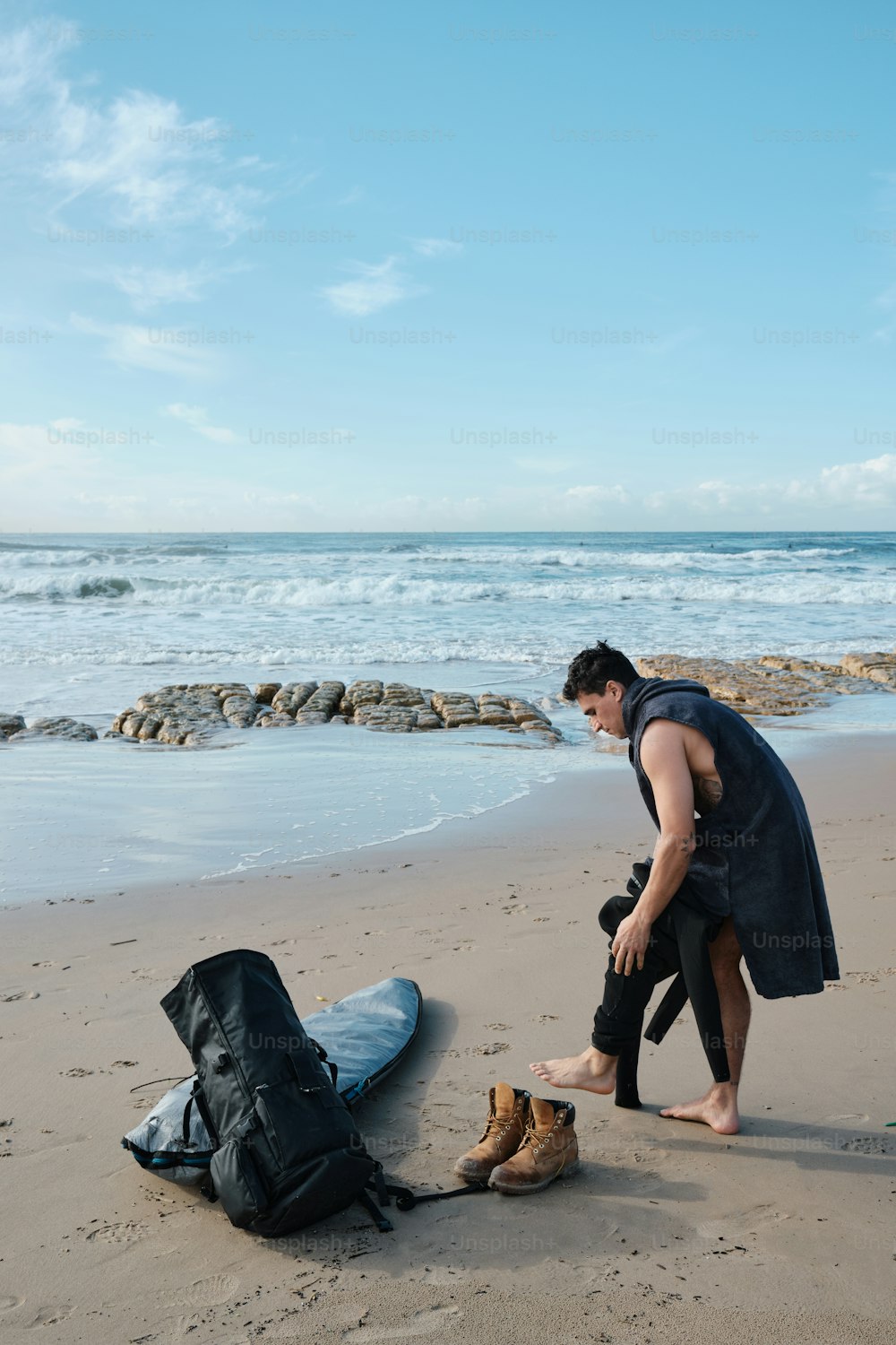 um homem em pé em uma praia ao lado de uma prancha de surf