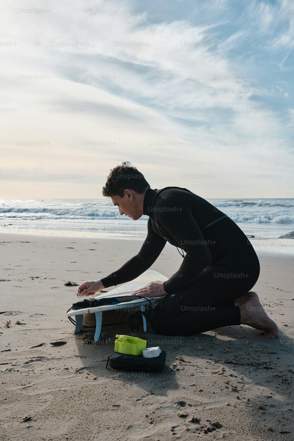 a man in a wet suit sitting on the beach