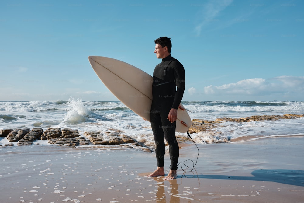 um homem em pé em uma praia segurando uma prancha de surf