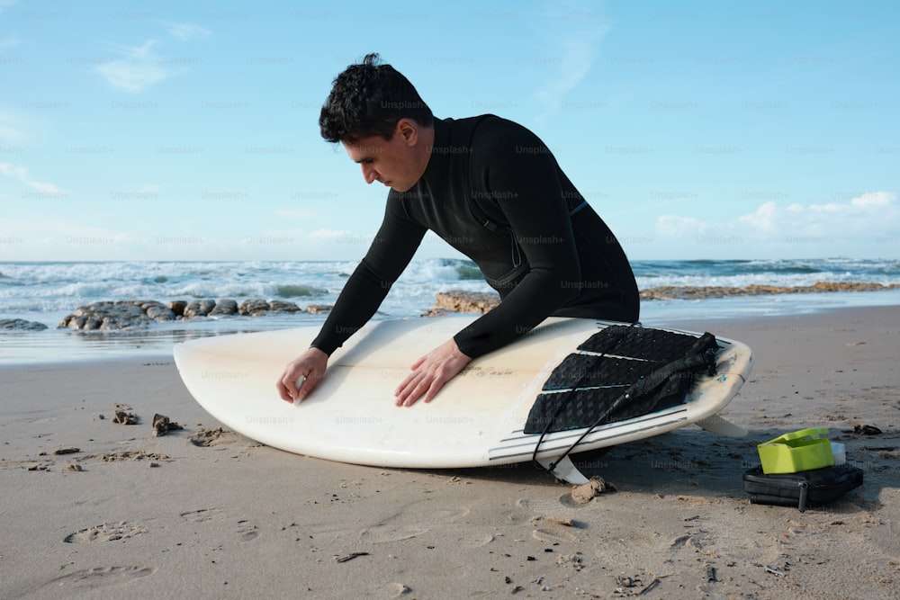um homem sentado em uma prancha de surf na praia