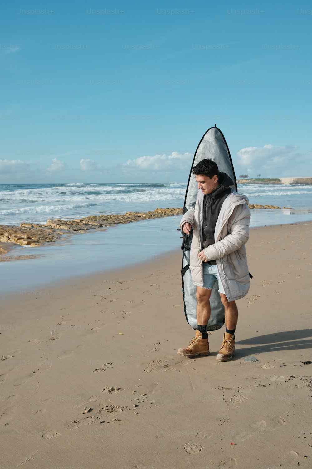 um homem em pé em uma praia segurando uma prancha de surf