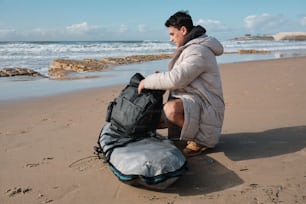 Un hombre sentado en la playa con una mochila