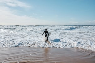 Una persona caminando hacia el océano con una tabla de surf