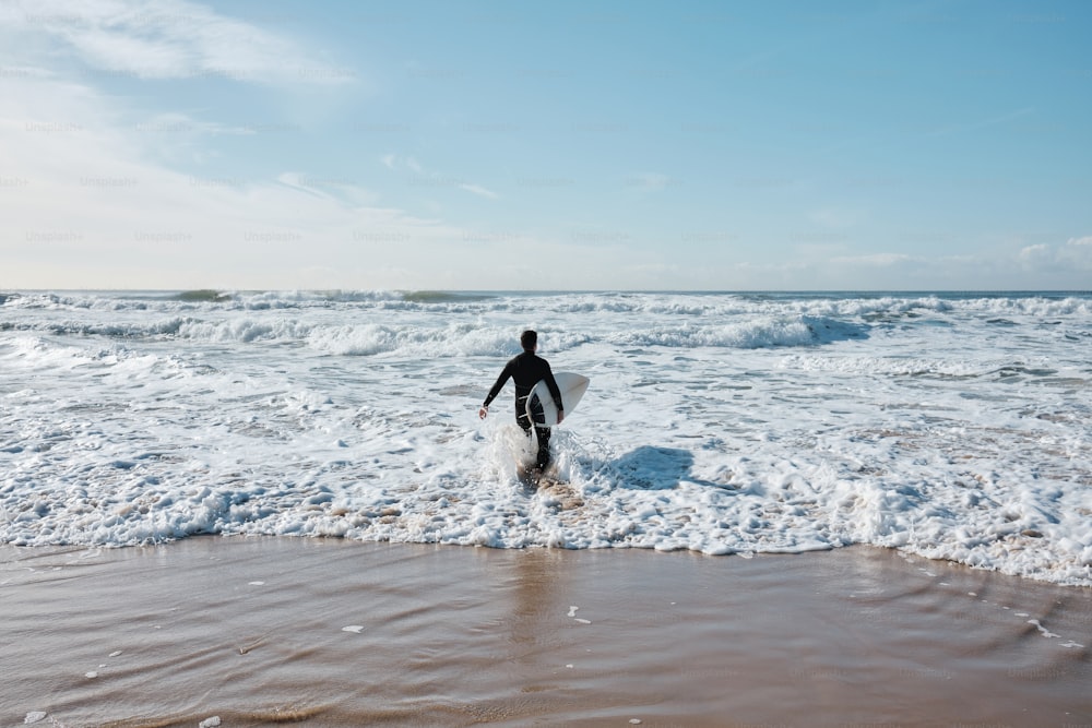 a person walking into the ocean with a surfboard