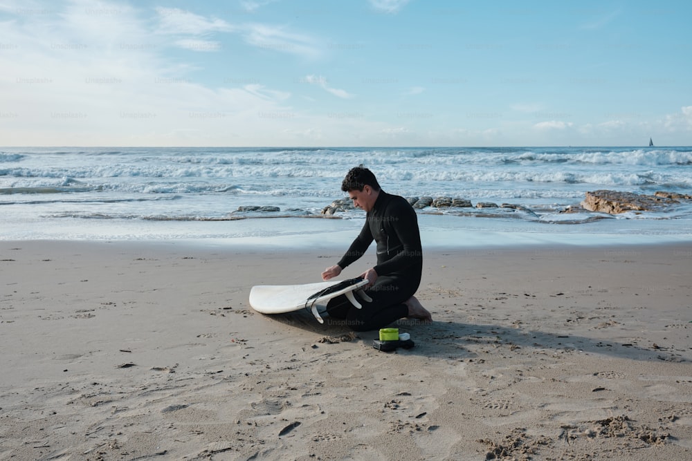 a man sitting on the beach with a surfboard