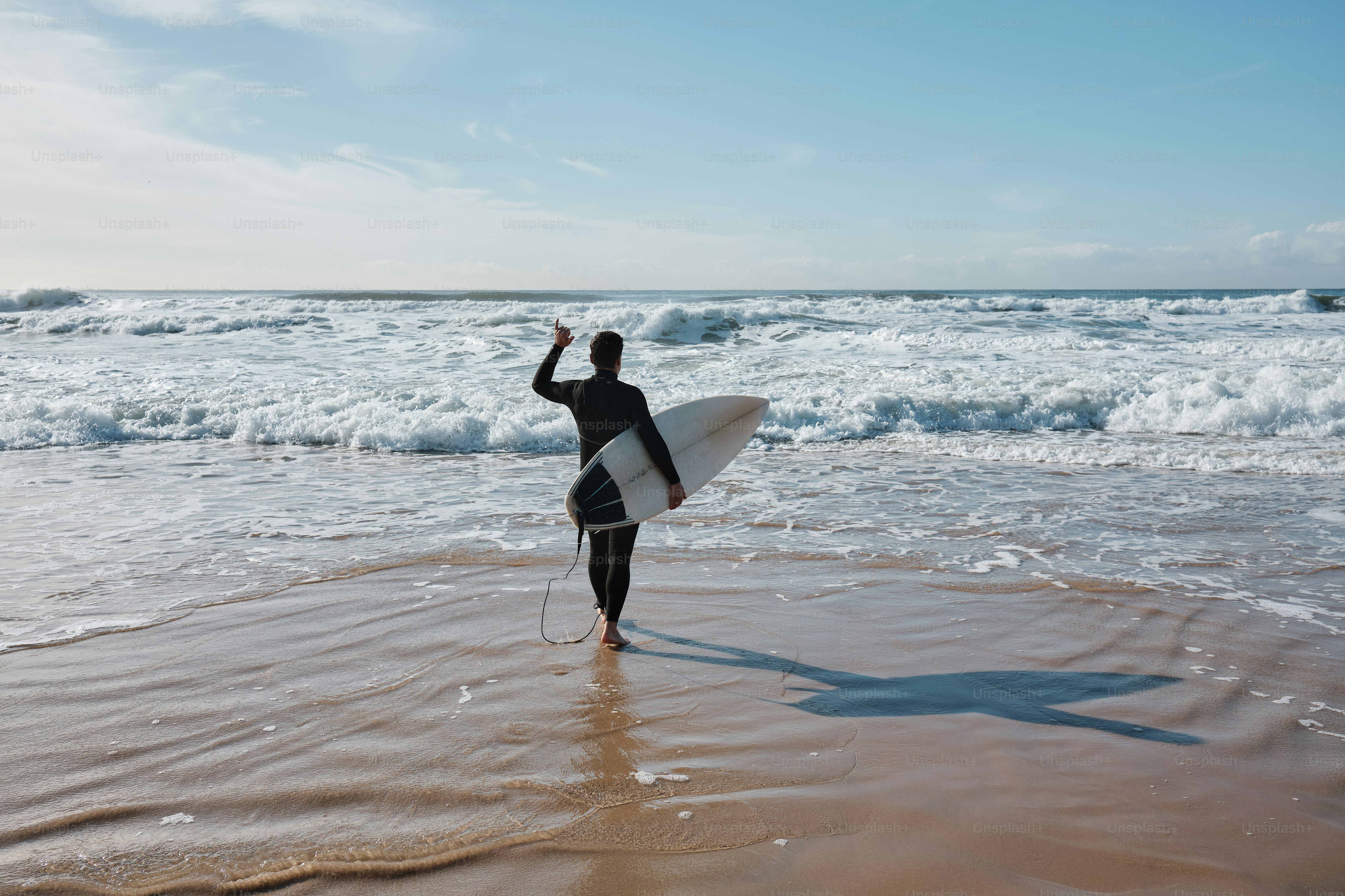 a man holding a surfboard on top of a sandy beach