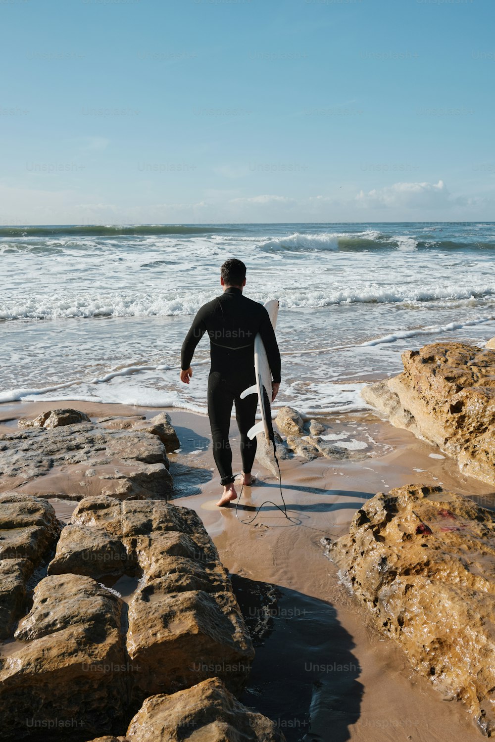 a man in a wet suit walking along the beach