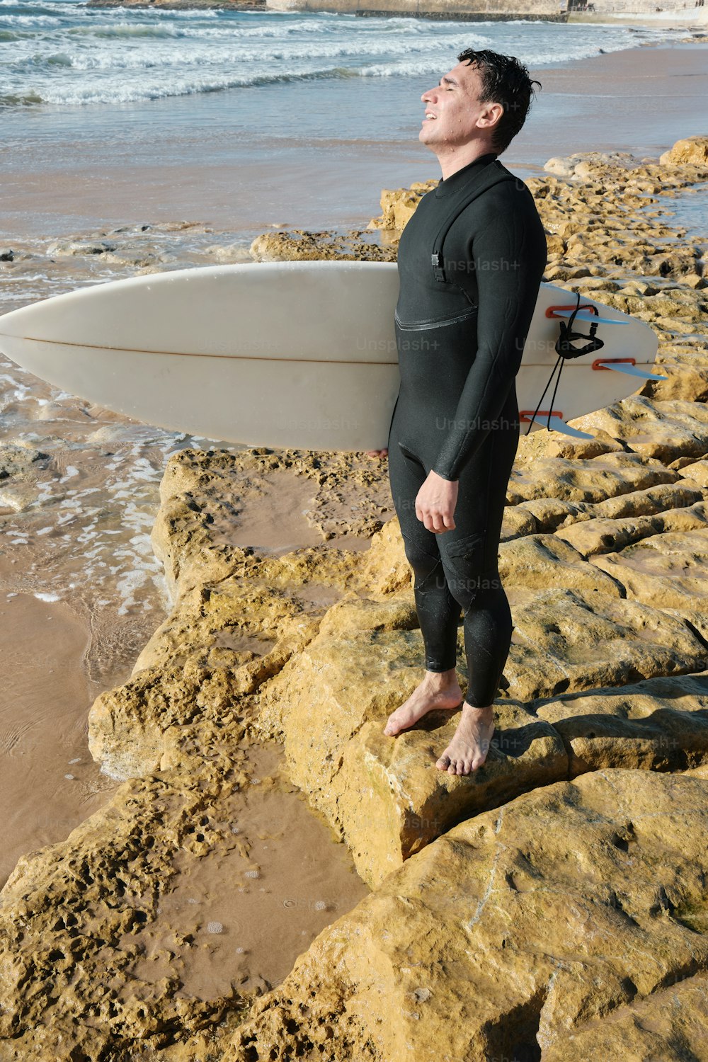 a man in a wet suit holding a surfboard