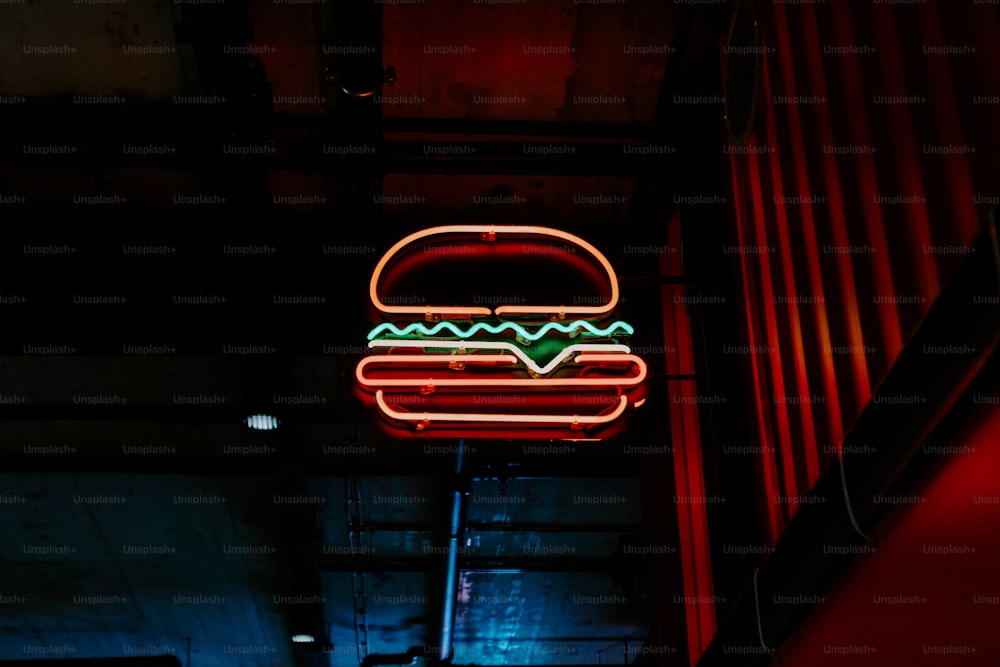 a neon hamburger sign hanging from the side of a building