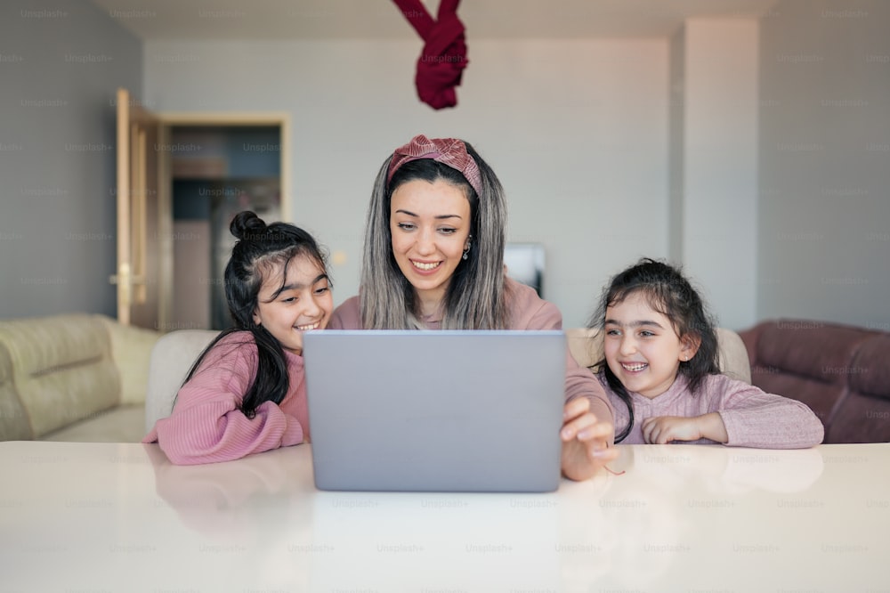 uma mulher e duas meninas olhando para um laptop