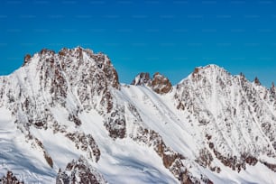 青空の下で雪に覆われた山々のグループ