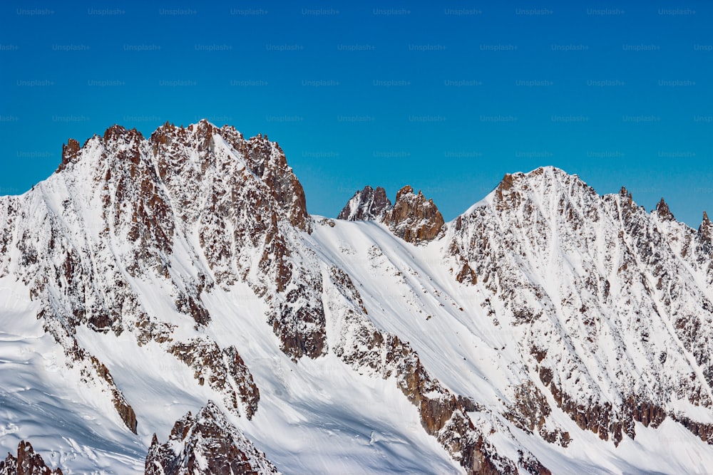 Un grupo de montañas cubiertas de nieve bajo un cielo azul