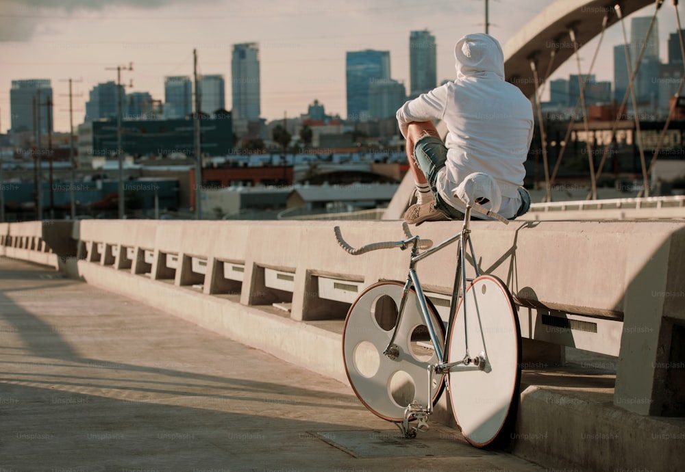 a man sitting on a bridge next to a bike