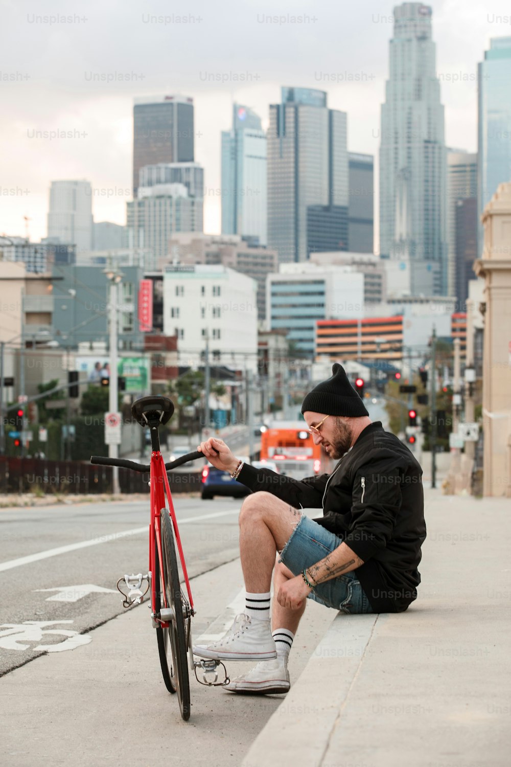Un uomo seduto sul ciglio di una strada accanto a una bicicletta