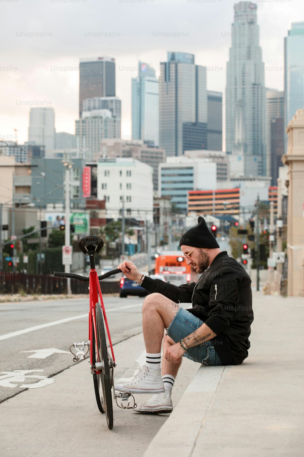 a man sitting on the side of a road next to a bike