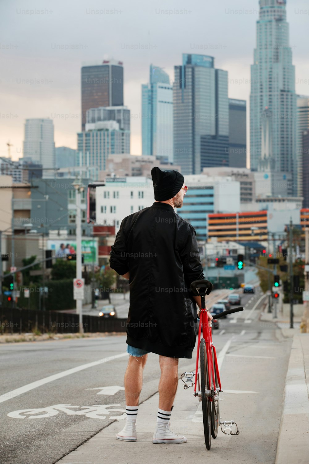 Un hombre con una chaqueta negra y una bicicleta roja