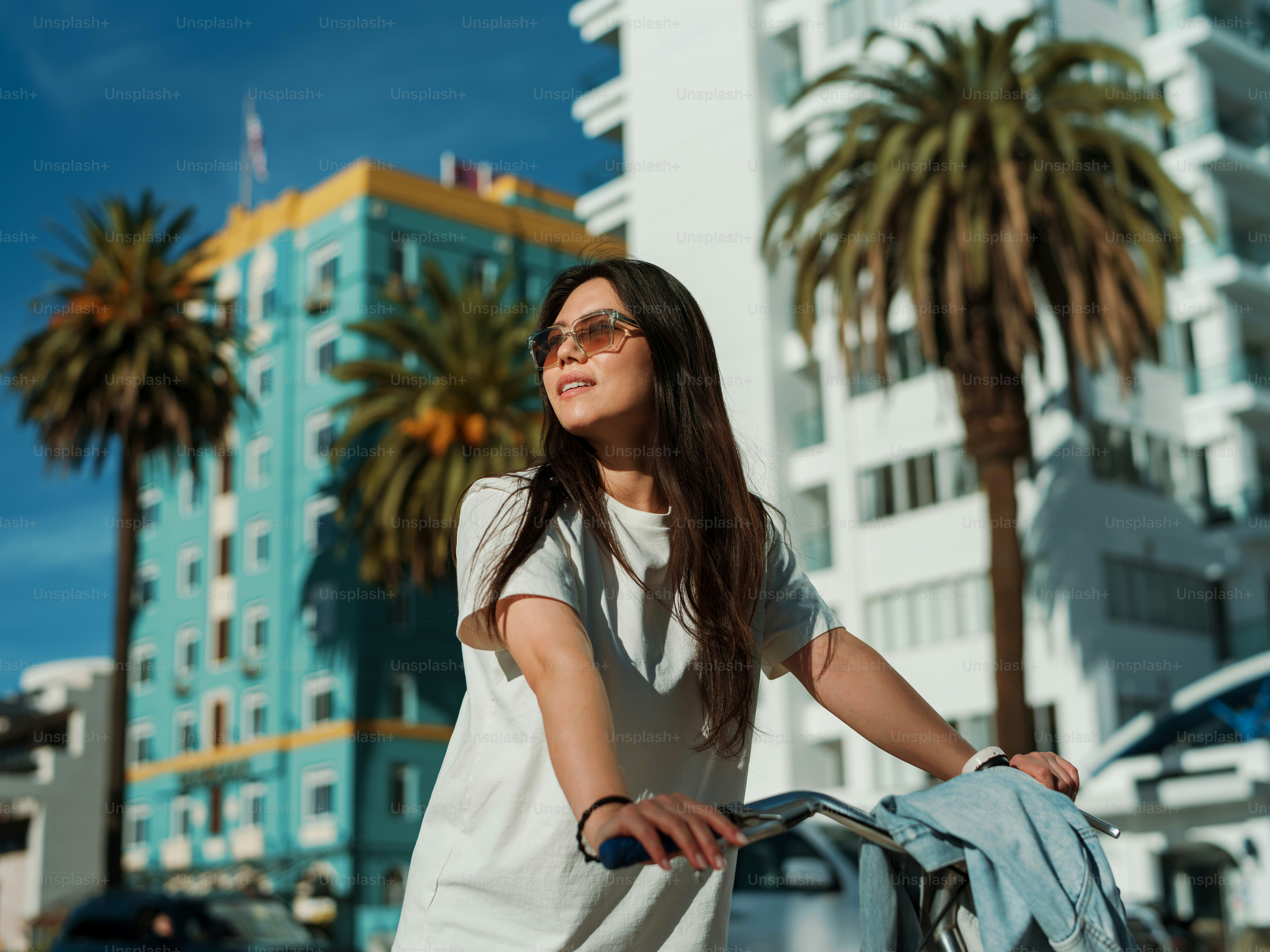uma mulher que anda de bicicleta por uma rua ao lado de palmeiras
