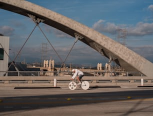 Ein Mann fährt mit dem Fahrrad eine Straße unter einer Brücke hinunter