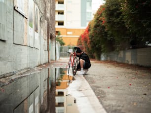 uma pessoa ajoelhada ao lado de uma bicicleta