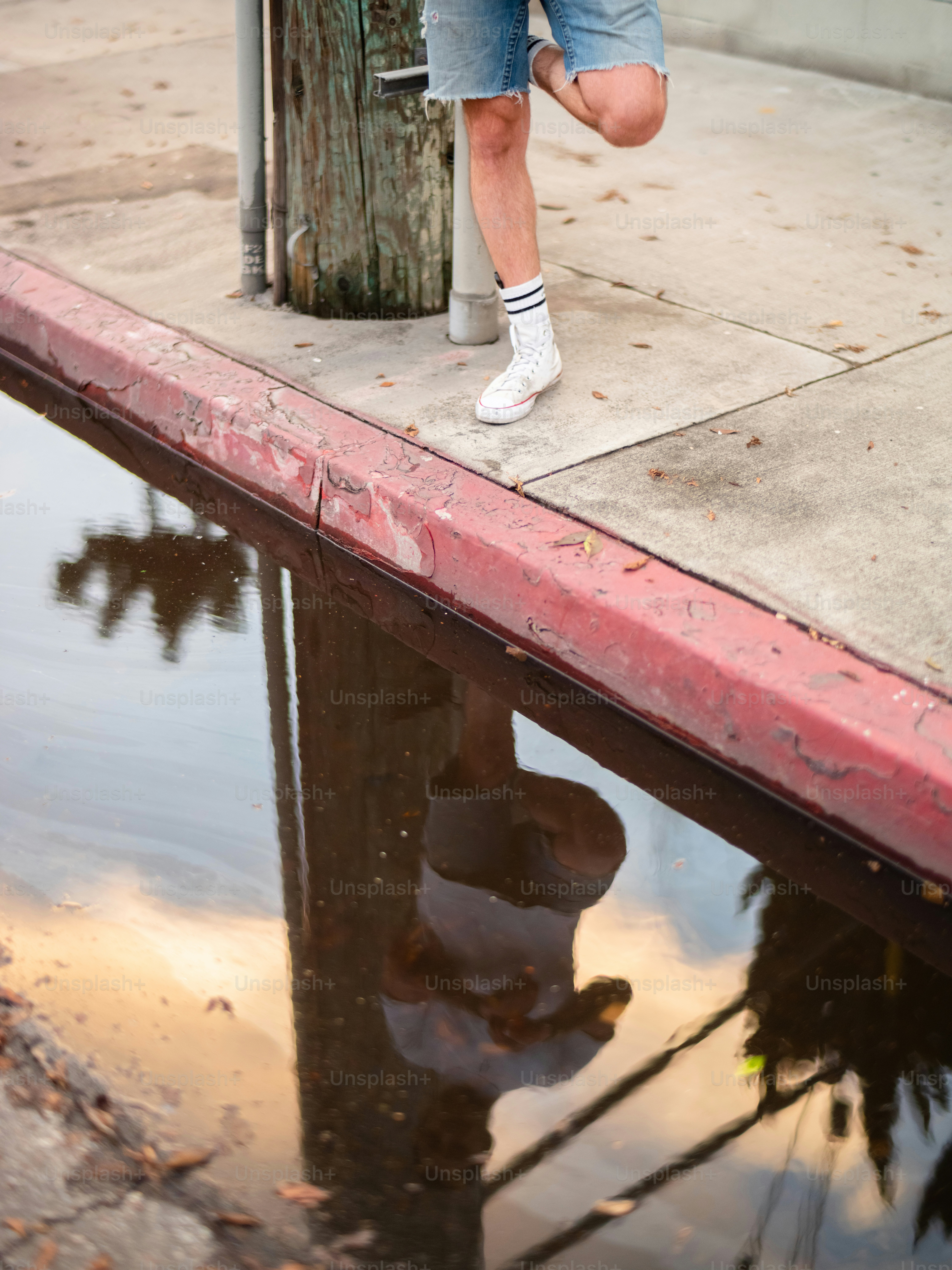 a man leaning against a pole on the side of a street