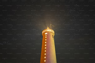 a light house lit up at night with stars in the sky