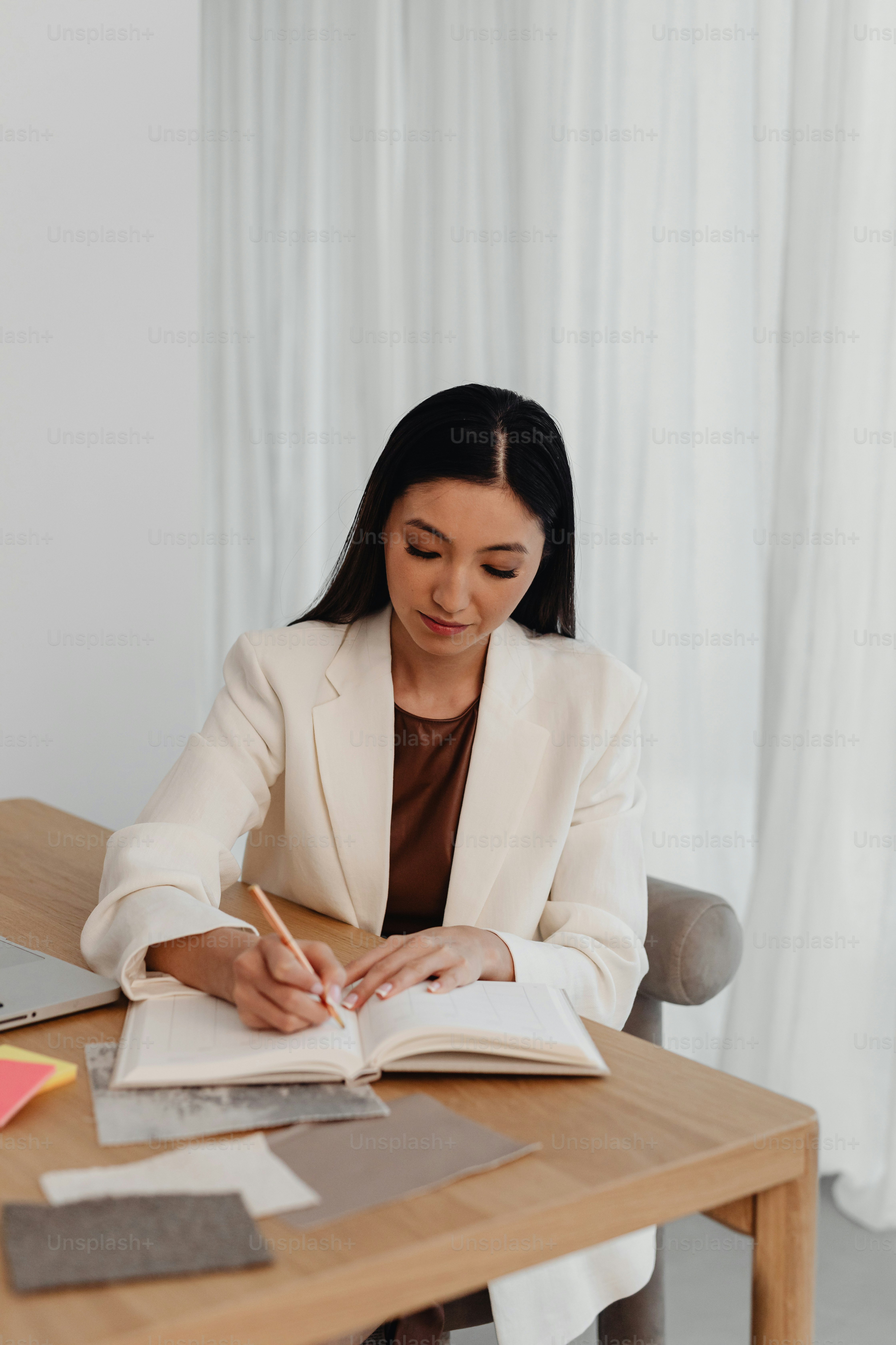 a woman sitting at a table with a book and pen