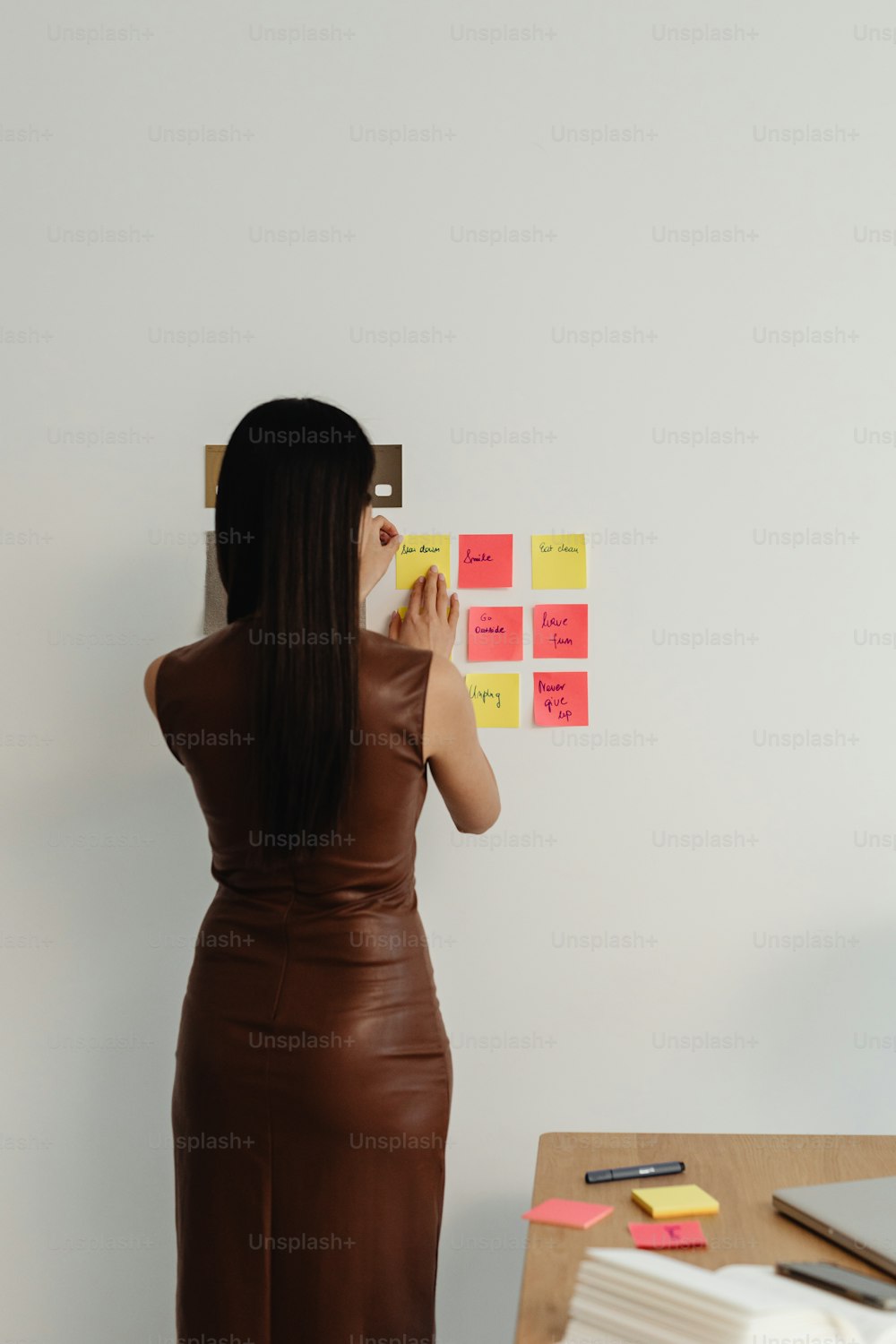 a woman standing in front of a wall with sticky notes on it