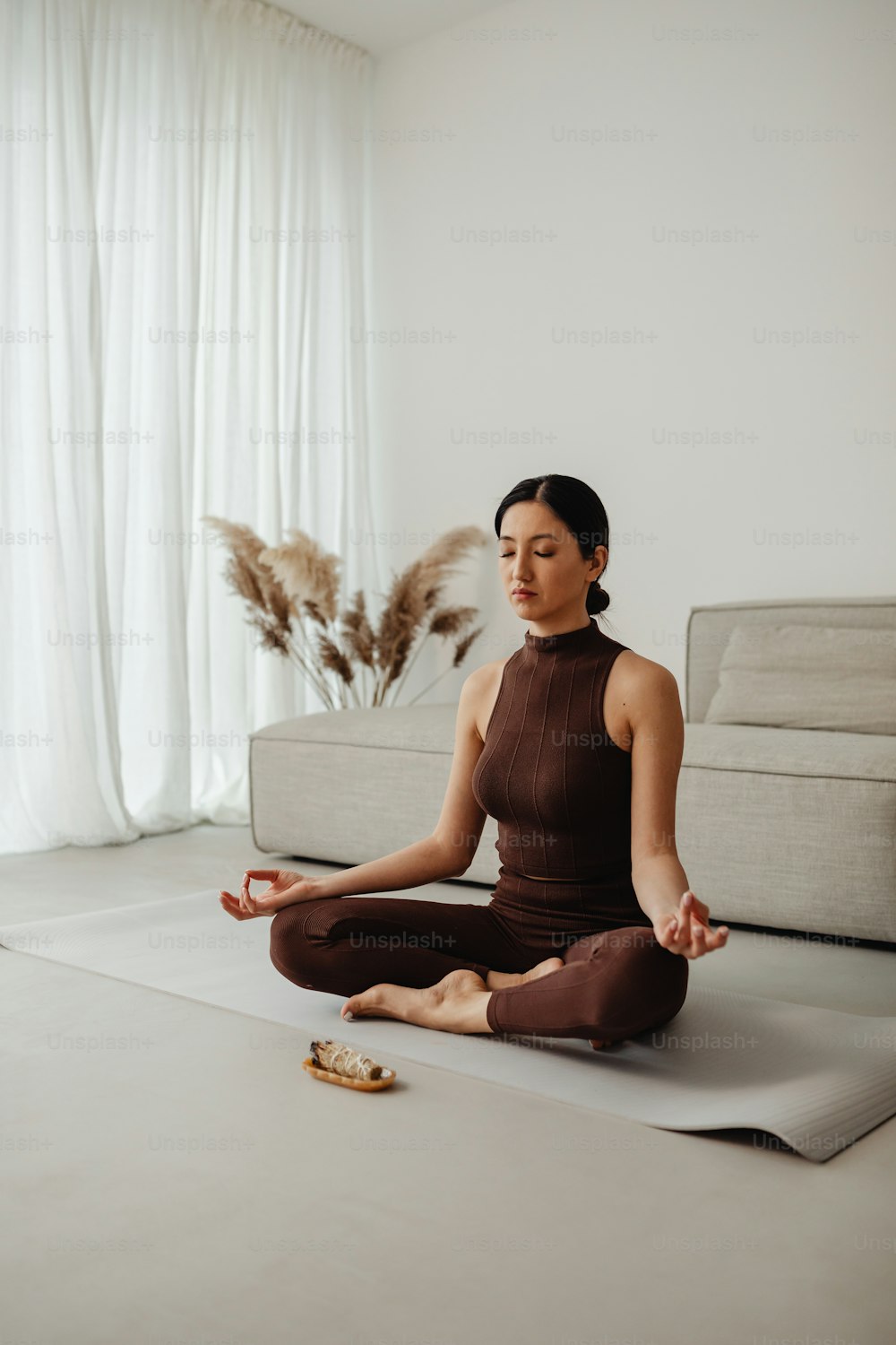Una mujer sentada en una esterilla de yoga en una sala de estar