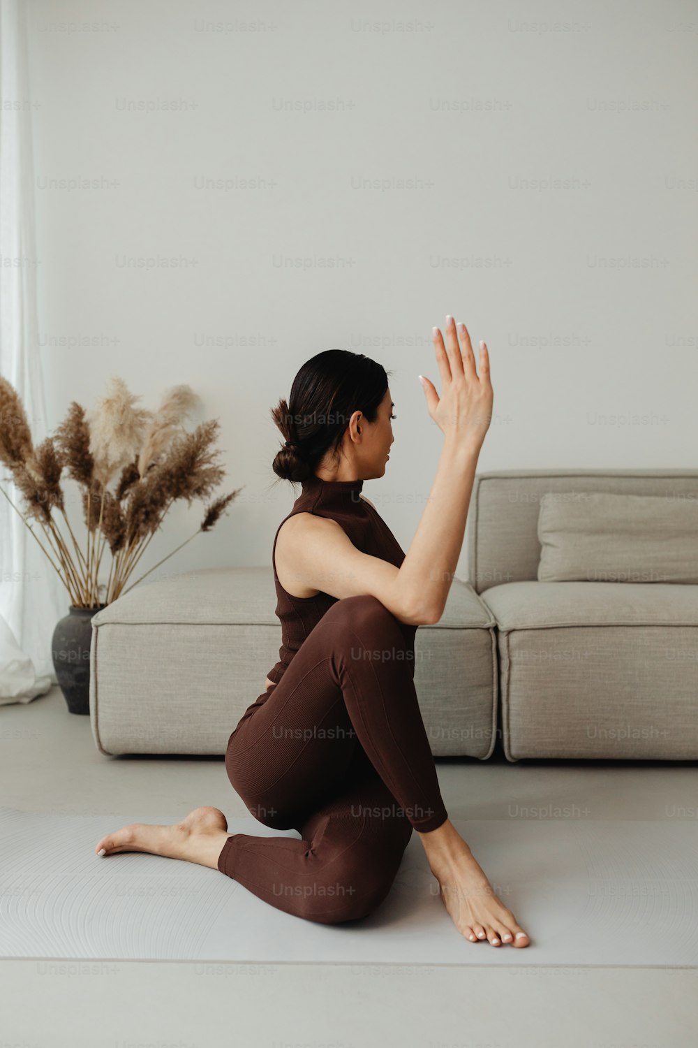a woman sitting on a yoga mat in front of a couch