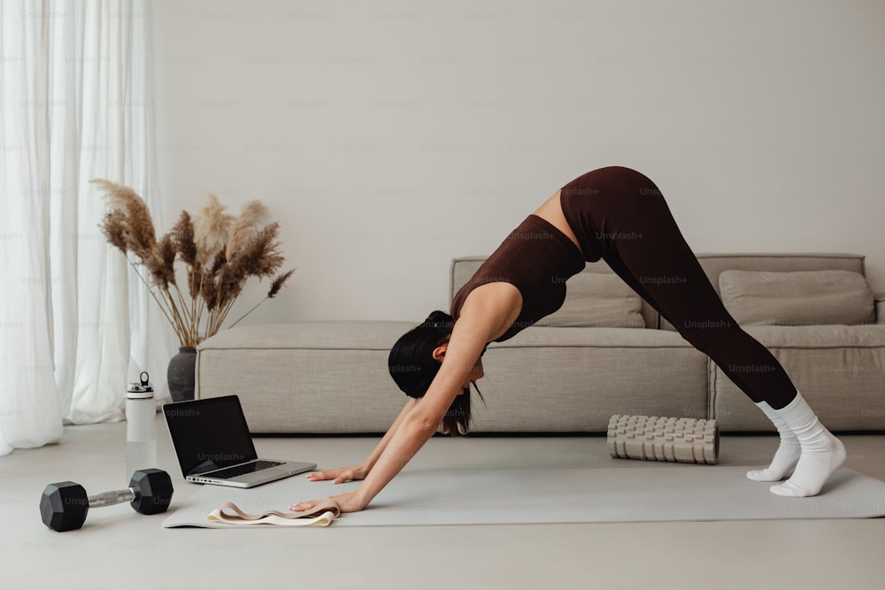 a woman doing a yoga pose in front of a laptop