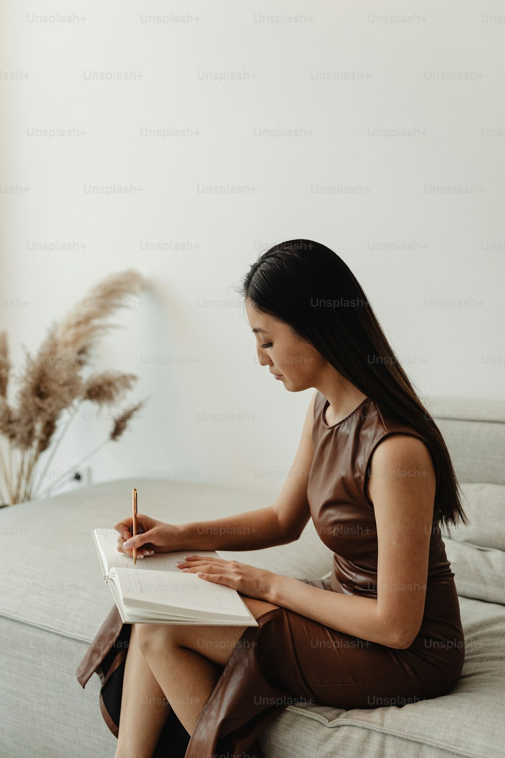 a woman sitting on a couch writing in a notebook