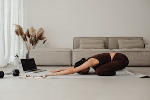 a woman is doing yoga in front of a laptop