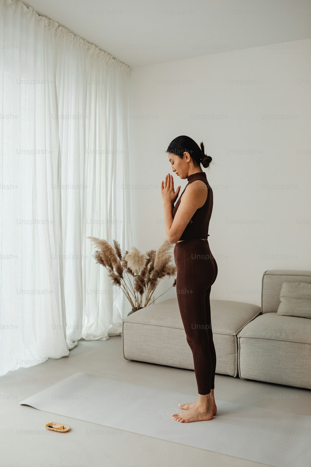 a woman standing on a yoga mat in front of a couch