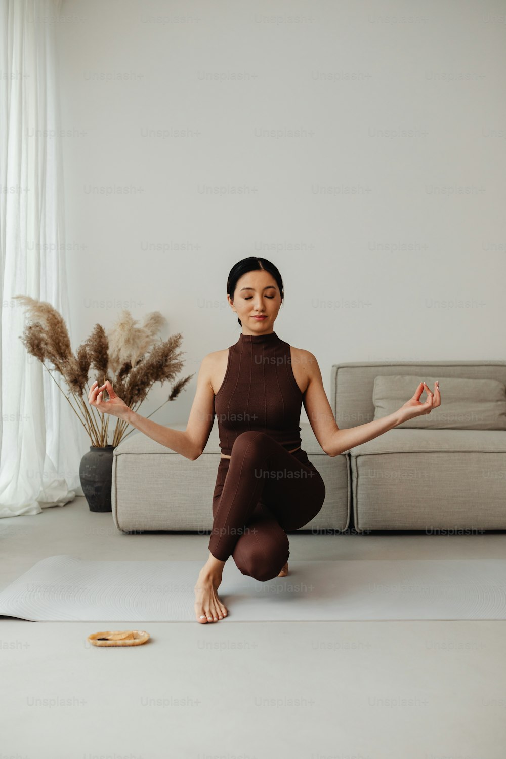 Una mujer está haciendo yoga frente a un sofá