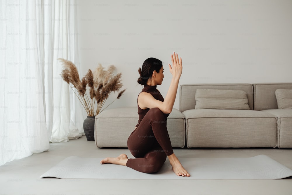 uma mulher sentada em um tapete de yoga em uma sala de estar