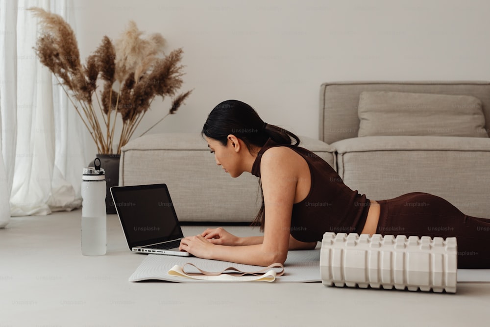 Una mujer tendida en el suelo usando una computadora portátil