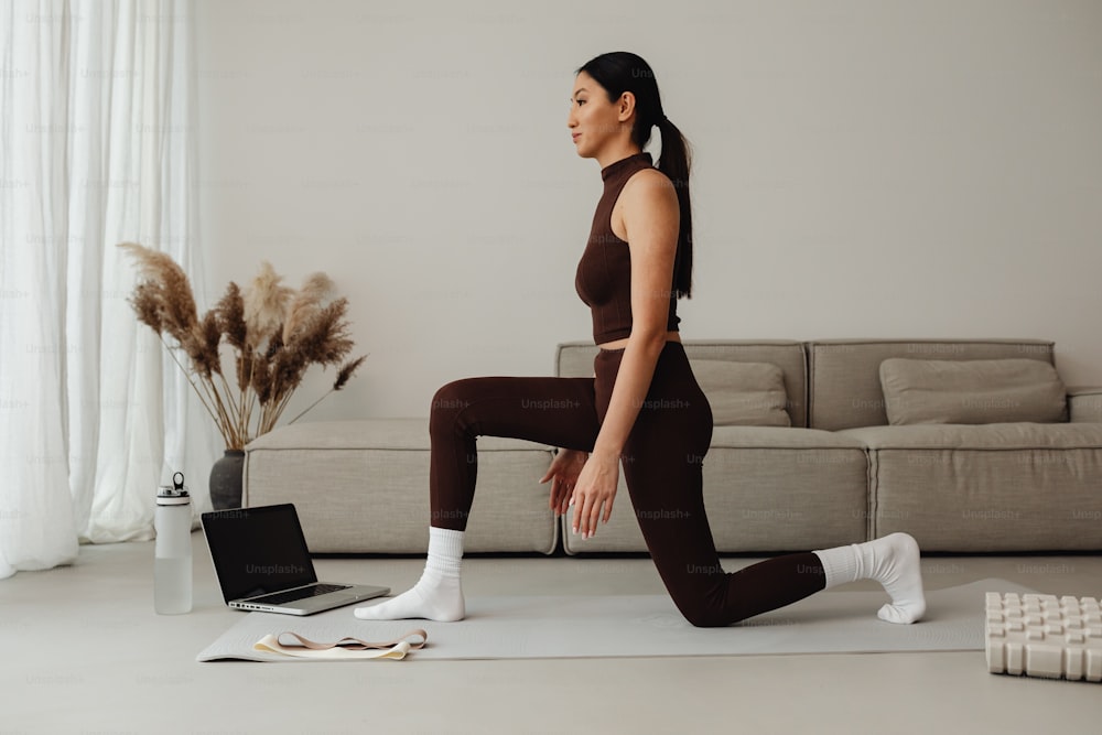 Una mujer con un top marrón y leggings haciendo yoga